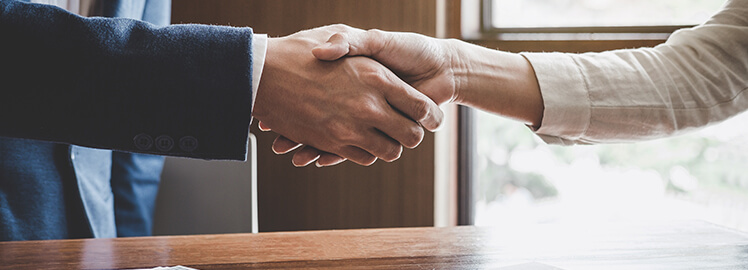 The arms of two real estate professionals shaking hands